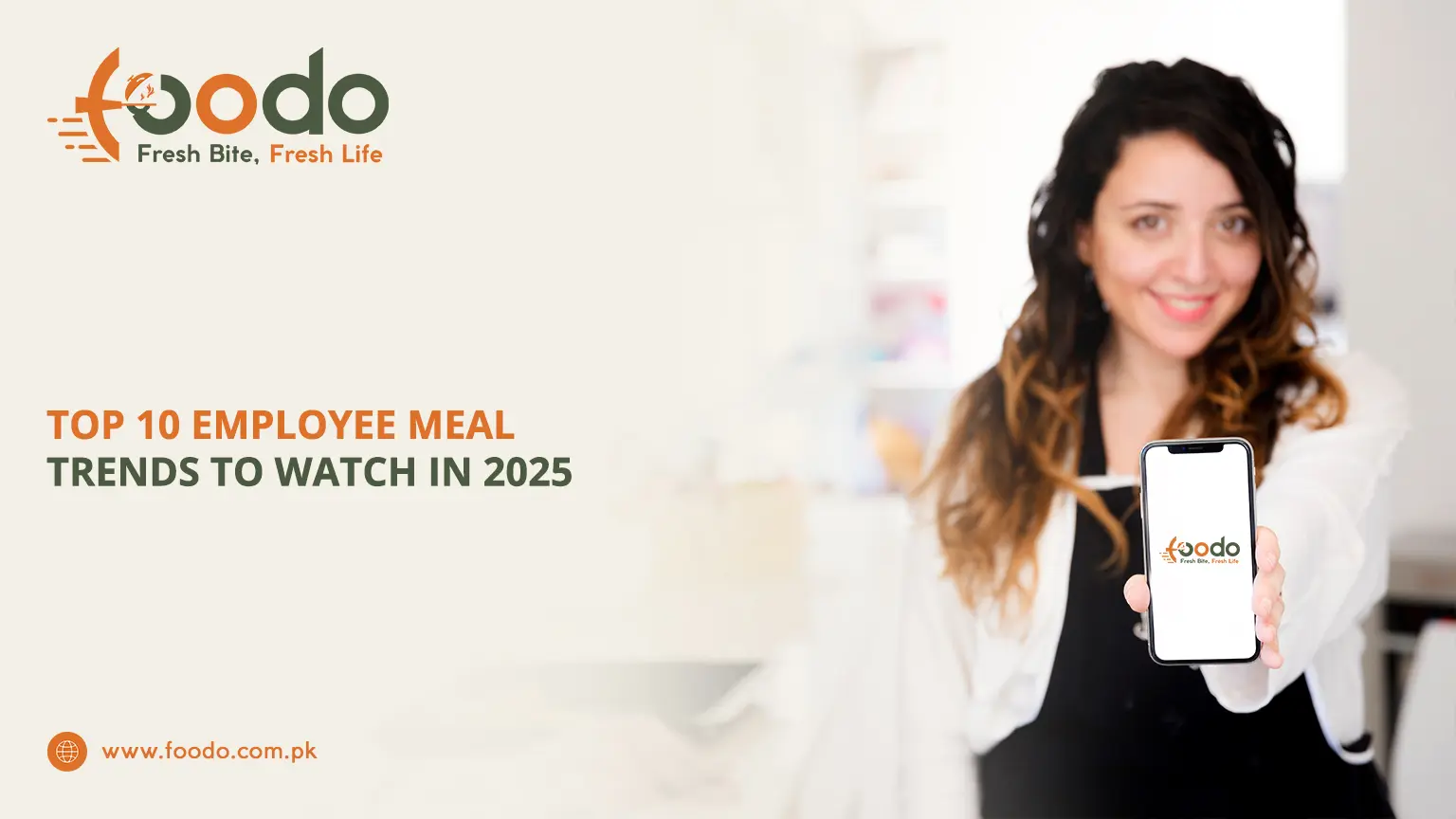 Smiling young professional woman holding smartphone displaying Foodo logo, standing in modern office kitchen with healthy employee meals in background, highlighting 2025 corporate meal trends